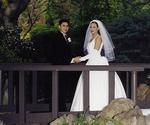 The gentleman walks his bride across a bridge.