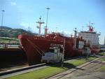 A ship in the Canal being lowered assisted by locomotives which guide the lines.