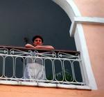 A maid takes a break to listen to the live music in the courtyard below.