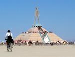People hike up the pyramid to view the Man in the daylight.