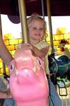 Grace rides a pink piggy.