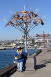 A woman reads next to "The Puzzle Tree."  This 23-piece jigsaw puzzle was created by John S. Stokes III and Bob Archer.