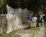 Fishermen repair their nets by hand.