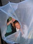 Cherie and Hannah peek out of their mosquito net.