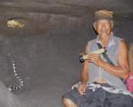 A Balinese man shines a light on one of the poisonous snakes in a cave near Tanah Lot.