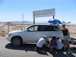 Jean gives the guys a little shade as they change a flat tire.