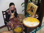 A silk-maker grabs a cocoon of silk.