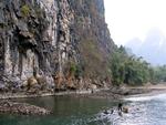 The fisherman is dwarfed by the massive spires of karst.