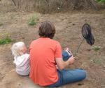 A father teaches his daughter how to catch a squirrel.