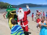Santa arrives to Long Island, Australia via jet ski.  It's too hot for the raindeer, so Santa brings a crocodile to help hand out gifts!