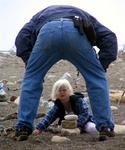 Dad helps Kylie build a rock structure.