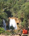 Monks rest near a waterfall.