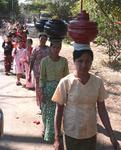 Women walking through the village with offerings to the monks. *Photo by Jean Leitner.