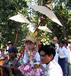 The children are draped in princely costumes and shaded by parasoles.