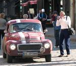 Photographers snap photos as the old cars drive past.