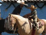 A father makes sure his young son is saddled up.