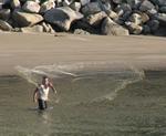 A local fisherman throws his net in the harbor.